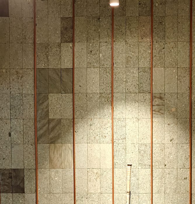 Sukabhumi Stone wall with copper strip accents at KAYU